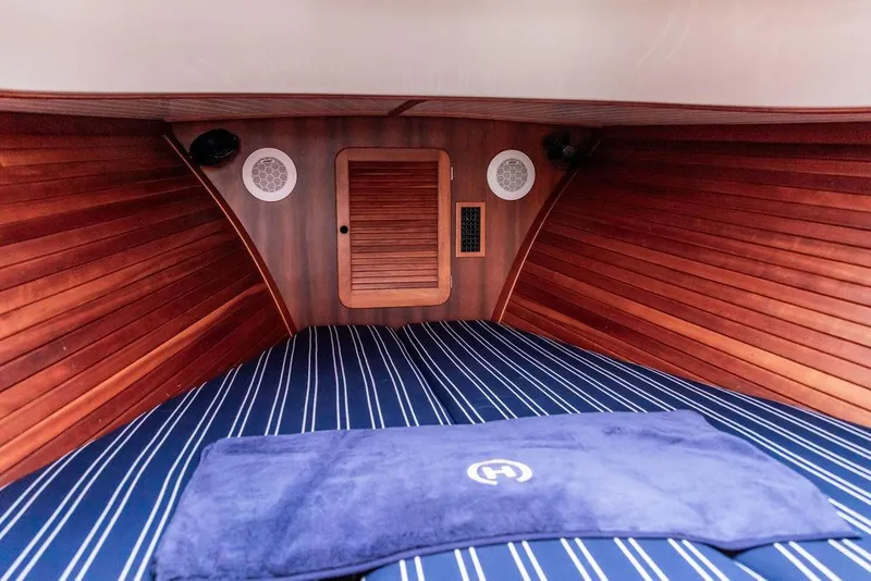 Slide: The Image of 1999 Hinckley Picnic Boat Classic cabin interior with wood paneling and striped bedding. - 19