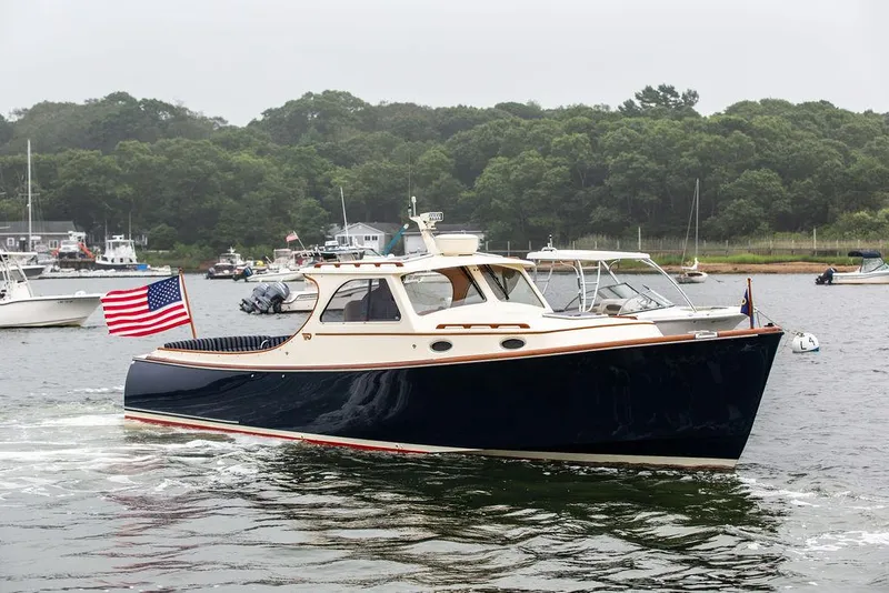 Slide: The Image of 1999 Hinckley Picnic Boat Classic cruising on a calm lake with American flag. - 2