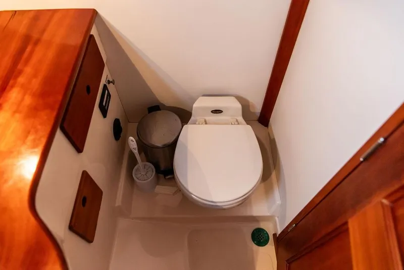 Slide: The Image of 1999 Hinckley Picnic Boat Classic bathroom with wooden accents and compact toilet. - 21