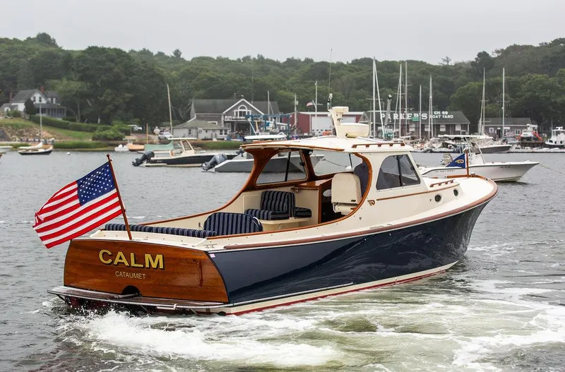 Slide: The Image of 1999 Hinckley Picnic Boat Classic cruising in a scenic harbor with American flag. - 3