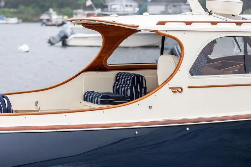 Slide: The Image of 1999 Hinckley Picnic Boat Classic with striped seating, cruising on a calm waterway. - 7