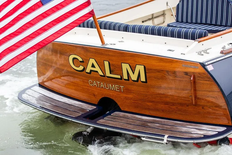 Slide: The Image of Hinckley Picnic Boat Classic 1999 with American flag, named "Calm," in Cataumet waters. - 8