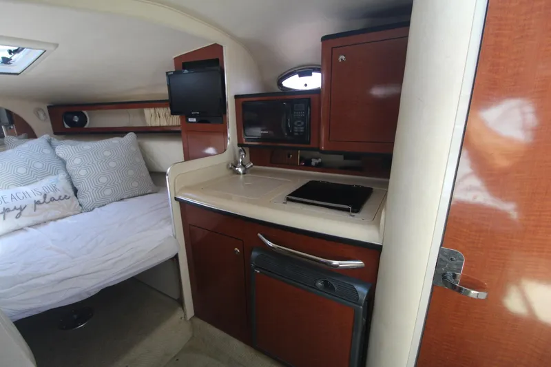 Slide: The Image of 2004 Sea Ray 280 Sundancer cabin interior with kitchenette, bed, and TV. - 12