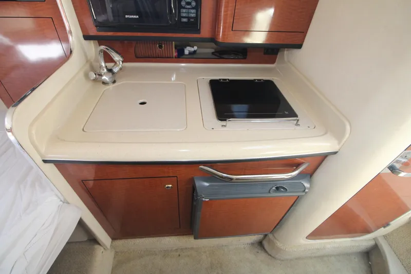 Slide: The Image of 2004 Sea Ray 280 Sundancer galley with sink, stove, and microwave. - 13