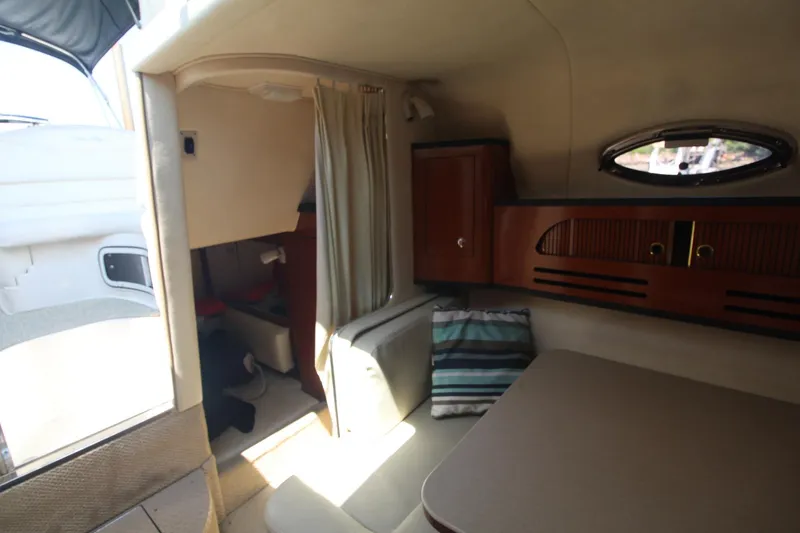 Slide: The Image of Interior of 2004 Sea Ray 280 Sundancer, featuring cozy seating and wooden cabinetry. - 17