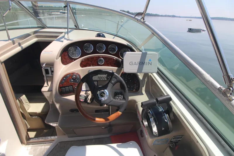 Slide: The Image of 2004 Sea Ray 280 Sundancer helm with Garmin navigation, wood accents, and lake view. - 2