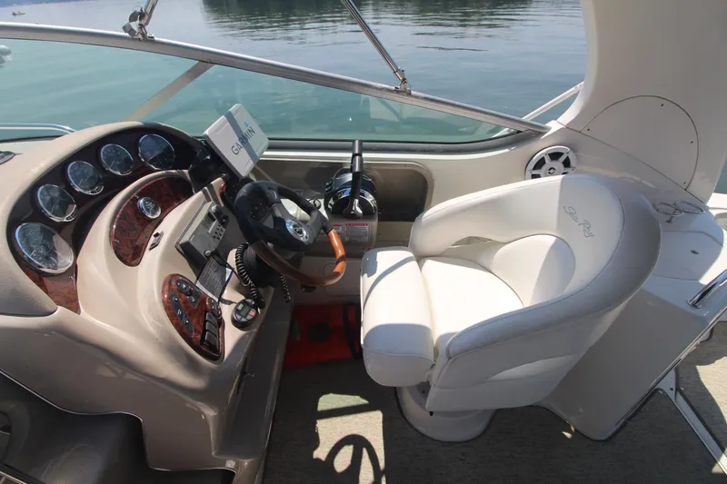 Slide: The Image of 2004 Sea Ray 280 Sundancer helm with steering wheel, gauges, and white captain's chair. - 5
