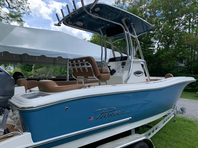 Slide: The Image of 2026 Pioneer 222 Islander boat with blue hull and T-top, displayed outdoors. - 3