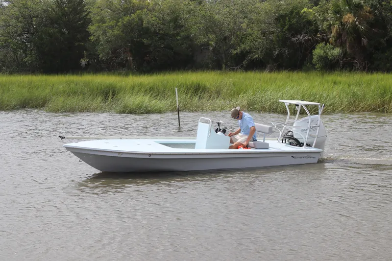 Slide: The Image of 2026 East Cape EVO 18V boat deck with storage hatch and paddle on calm water. - 3