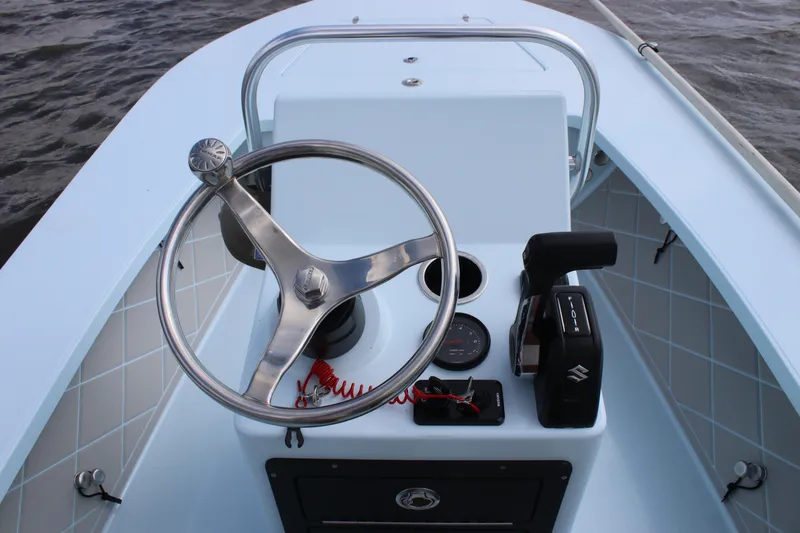Slide: The Image of 2026 East Cape EVO 18V boat console with storage compartment and steering wheel on water. - 8