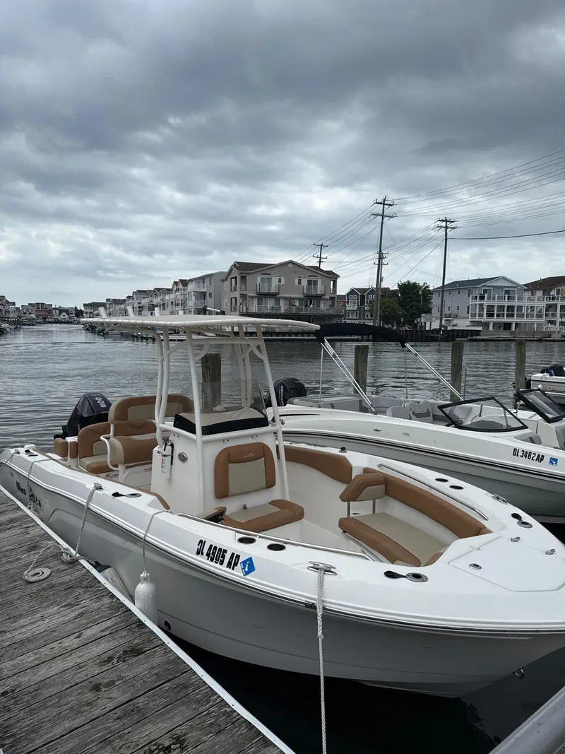 Slide: The Image of 2023 NauticStar 22L boat docked by waterfront homes under cloudy skies. - 11