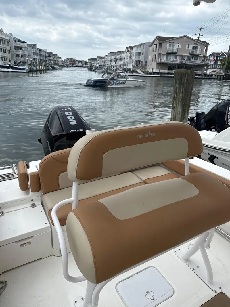 Slide: The Image of 2023 NauticStar 22L boat with tan seating, docked in a residential canal. - 3