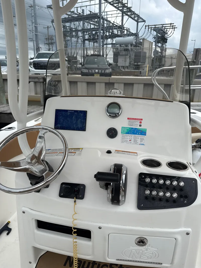 Slide: The Image of 2023 NauticStar 22L boat dashboard with steering wheel, controls, and gauges. - 5