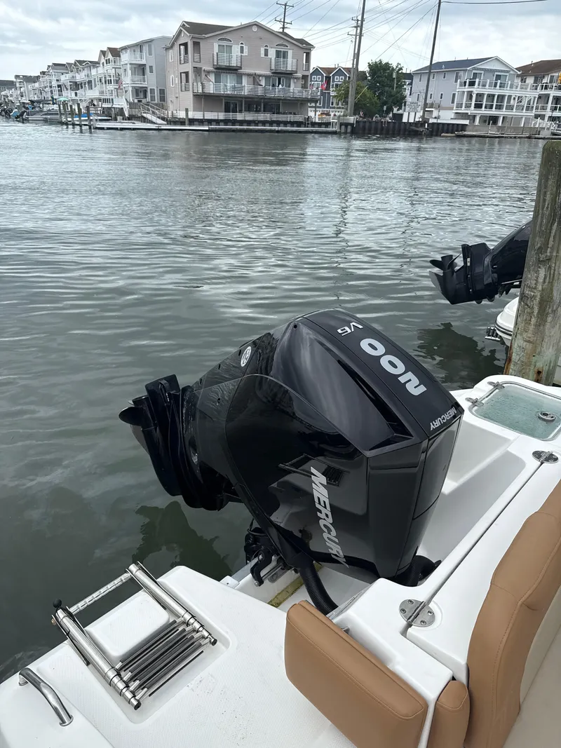 Slide: The Image of 2023 NauticStar 22L boat with Mercury 200 V6 engine docked by waterfront homes. - 8