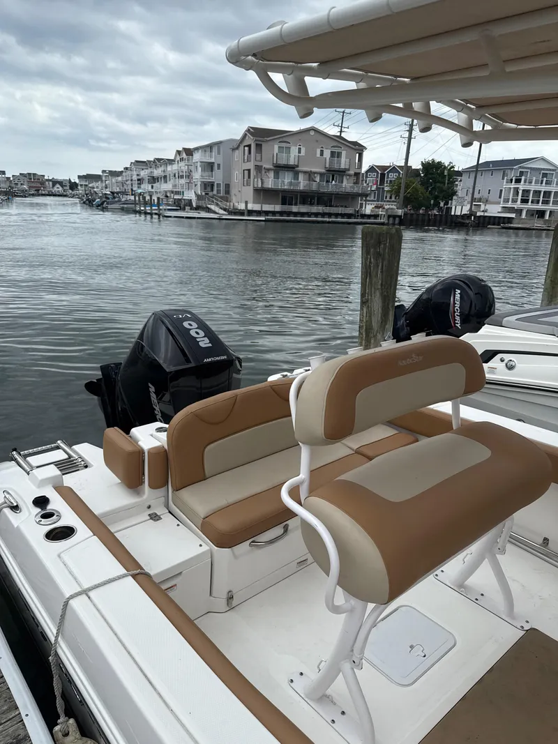 Slide: The Image of 2023 NauticStar 22L boat docked by waterfront homes under cloudy skies. - 9