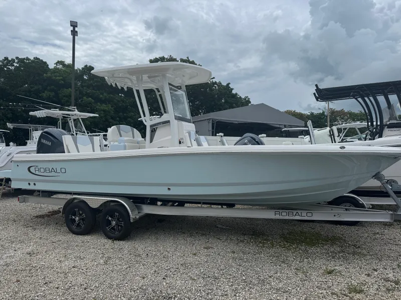 The Image of 2025 Robalo 246 Cayman boat on trailer, parked outdoors under cloudy sky. - 1