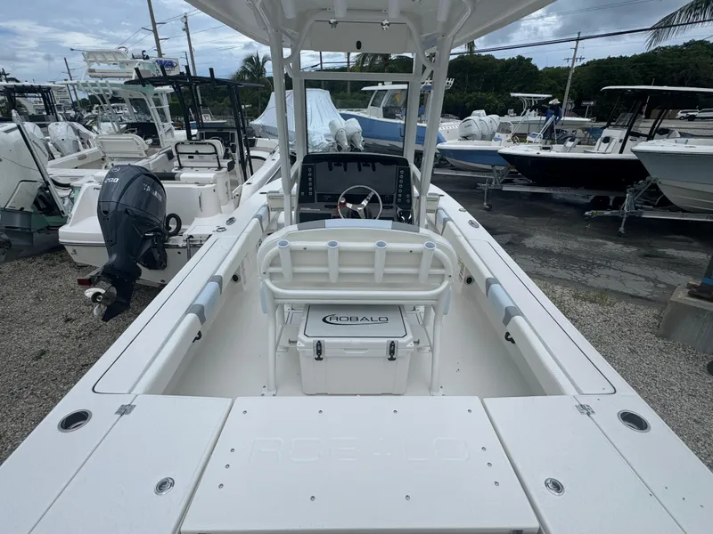 Slide: The Image of 2025 Robalo 246 Cayman boat interior with steering console and seating, displayed in a marina. - 3