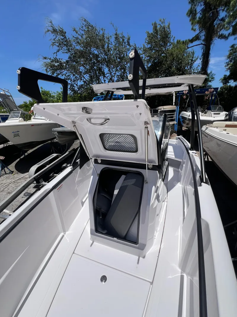 Slide: The Image of 2022 Axopar 22 T-Top boat with open storage compartment, docked outdoors. - 10