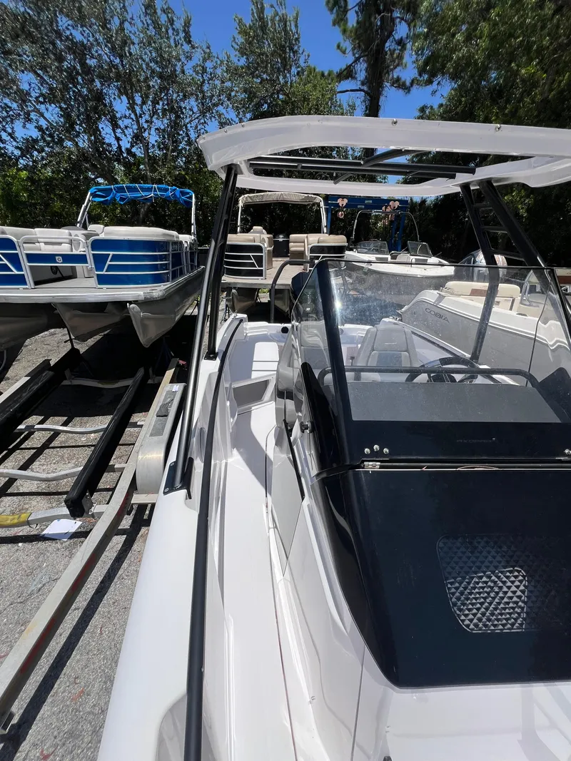 Slide: The Image of 2022 Axopar 22 T-Top boat on trailer, surrounded by other boats, in a wooded area. - 11