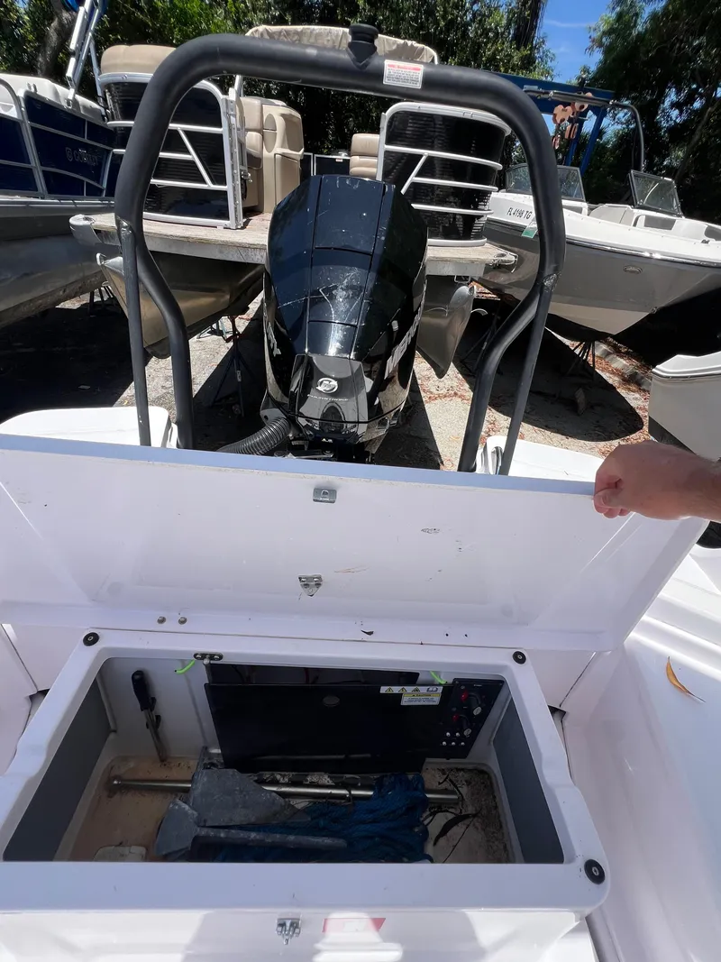 Slide: The Image of 2022 Axopar 22 T-Top boat with open storage compartment and visible outboard motor. - 14