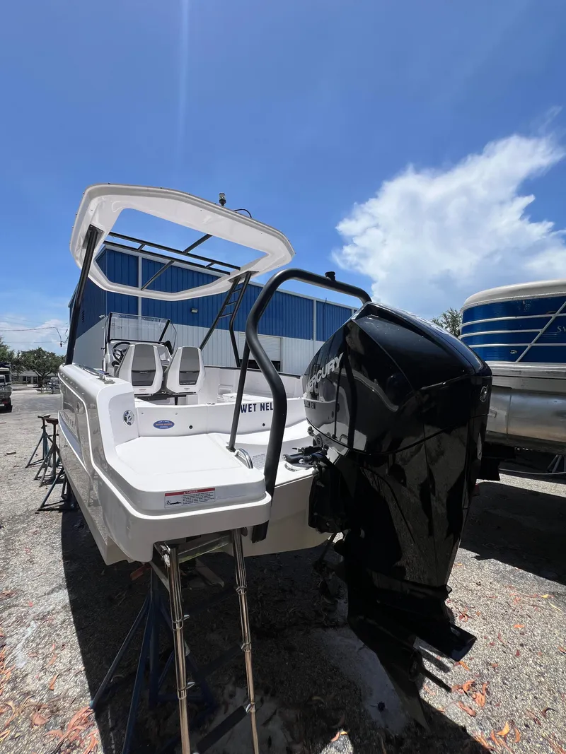 Slide: The Image of 2022 Axopar 22 T-Top boat with Mercury engine, parked outdoors under a clear blue sky. - 19