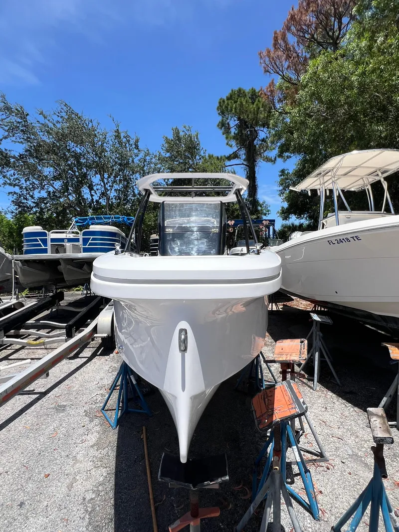 Slide: The Image of 2022 Axopar 22 T-Top boat on stands, surrounded by trees and other boats. - 24
