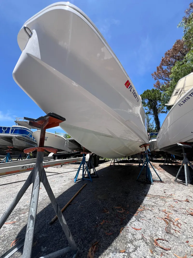Slide: The Image of 2022 Axopar 22 T-Top boat on stands, viewed from below, under clear blue sky. - 26
