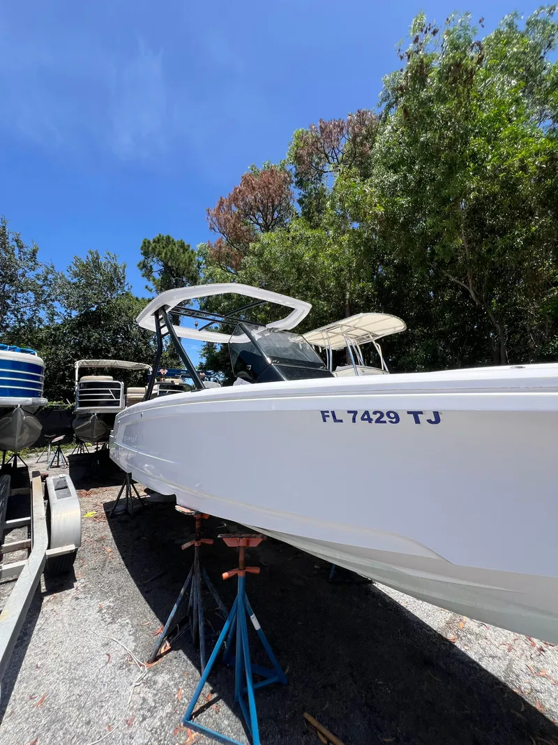 Slide: The Image of 2022 Axopar 22 T-Top boat on stands, surrounded by trees and clear blue sky. - 27