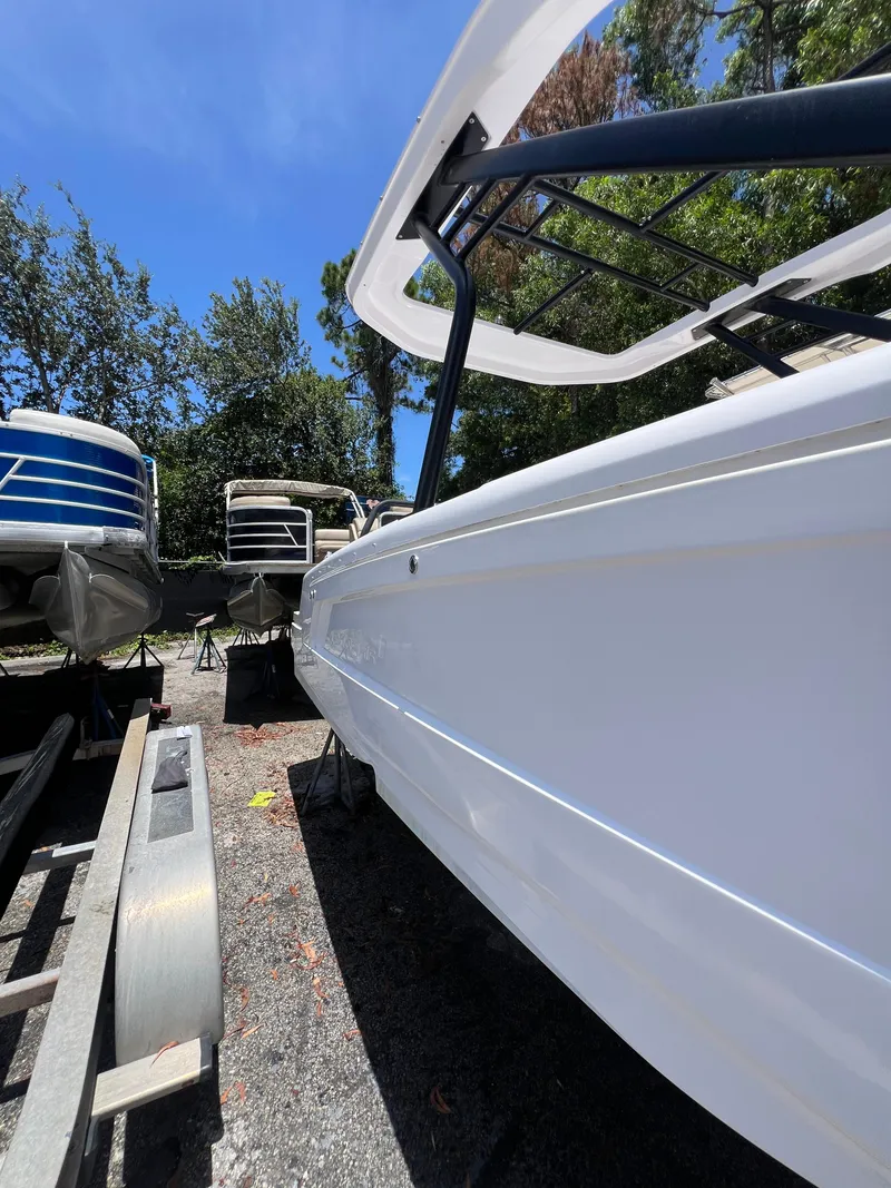 Slide: The Image of 2022 Axopar 22 T-Top boat on trailer, surrounded by trees and other boats. - 28