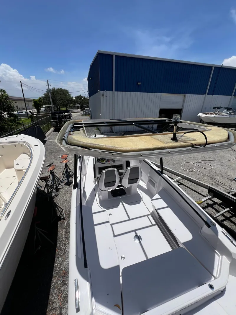 Slide: The Image of 2022 Axopar 22 T-Top boat in a marina, under a clear blue sky. - 33