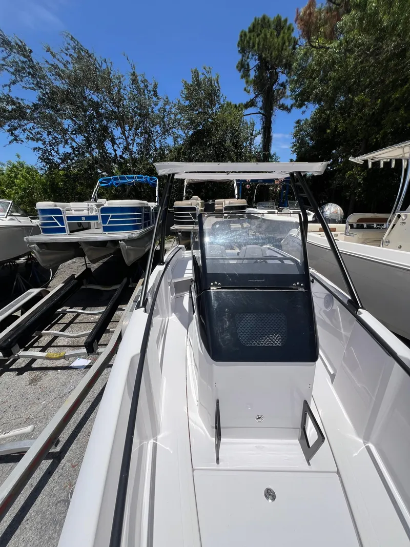 Slide: The Image of 2022 Axopar 22 T-Top boat on trailer, surrounded by trees and other boats. - 4