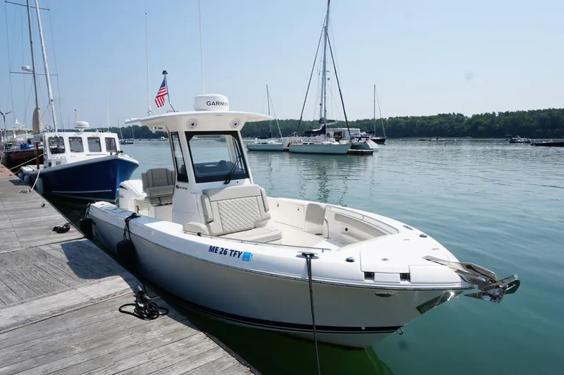 The Image of 2024 Pursuit S 248 Sport boat docked at marina with calm water and clear sky. - 1