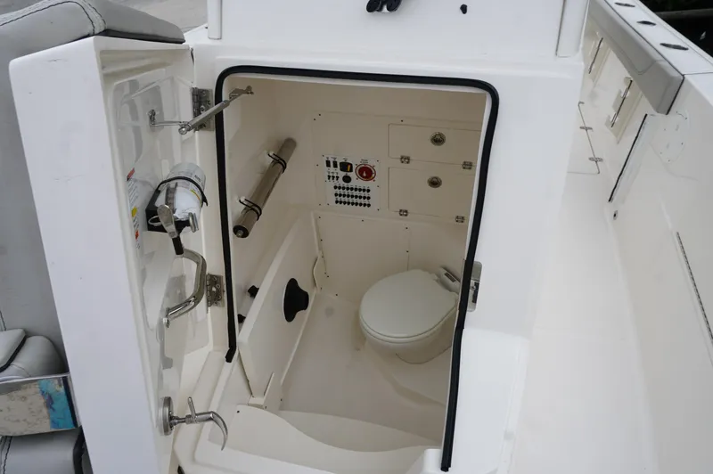 Slide: The Image of 2024 Pursuit S 248 Sport boat interior with compact marine toilet and storage. - 14