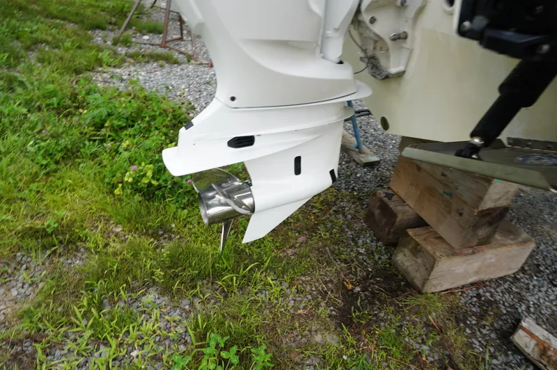 Slide: The Image of 2024 Pursuit S 248 Sport boat engine on wooden blocks, grassy and gravel background. - 7