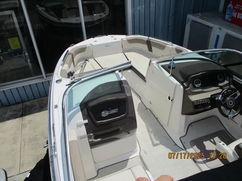 Slide: The Image of 2019 Chaparral 210 Suncoast boat interior with seating and dashboard, docked near a building. - 18