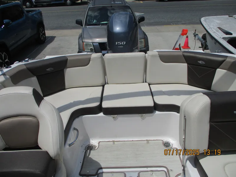 Slide: The Image of 2019 Chaparral 210 Suncoast boat interior with cushioned seating and outboard motor. - 20