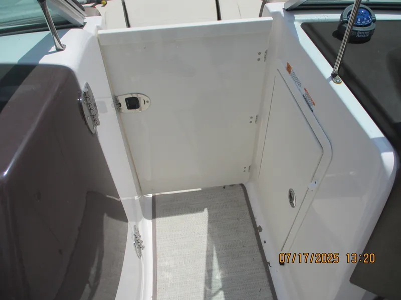Slide: The Image of 2019 Chaparral 210 Suncoast boat interior with open door and storage compartment. - 23