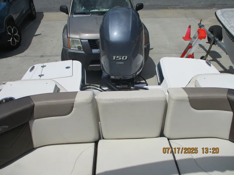 Slide: The Image of 2019 Chaparral 210 Suncoast boat with Yamaha 150 engine, parked near vehicles. - 27