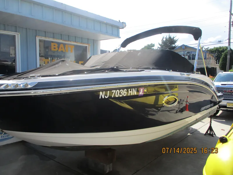 Slide: The Image of 2019 Chaparral 210 Suncoast boat with cover, parked near a bait shop. - 5