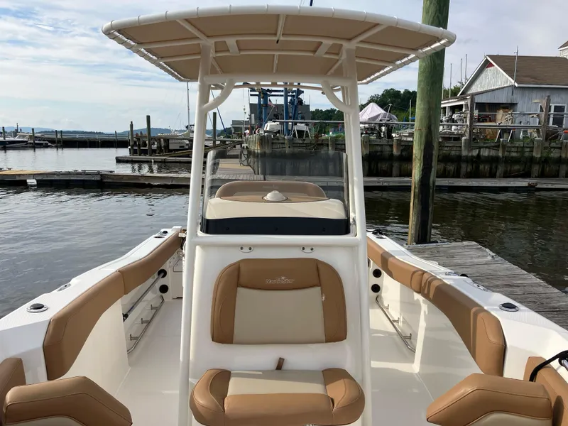 Slide: The Image of 2023 NauticStar 22L boat with tan seating, docked at a marina. - 6