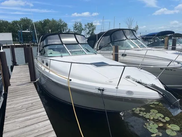 The Image of 1998 Sea Ray 290 Sundancer docked at marina, clear sky, calm water, nearby boats. - 1