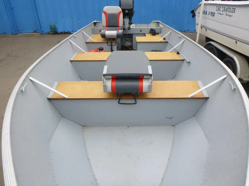 Slide: The Image of 2022 Lund SSV-16 boat interior with seating and motor, parked near a blue wall. - 6