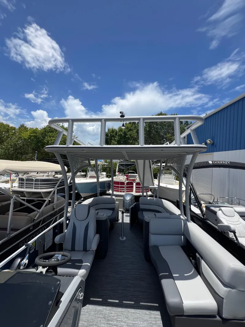 Slide: The Image of 2022 Godfrey Monaco 235 SDB pontoon boat with spacious seating under a clear blue sky. - 10