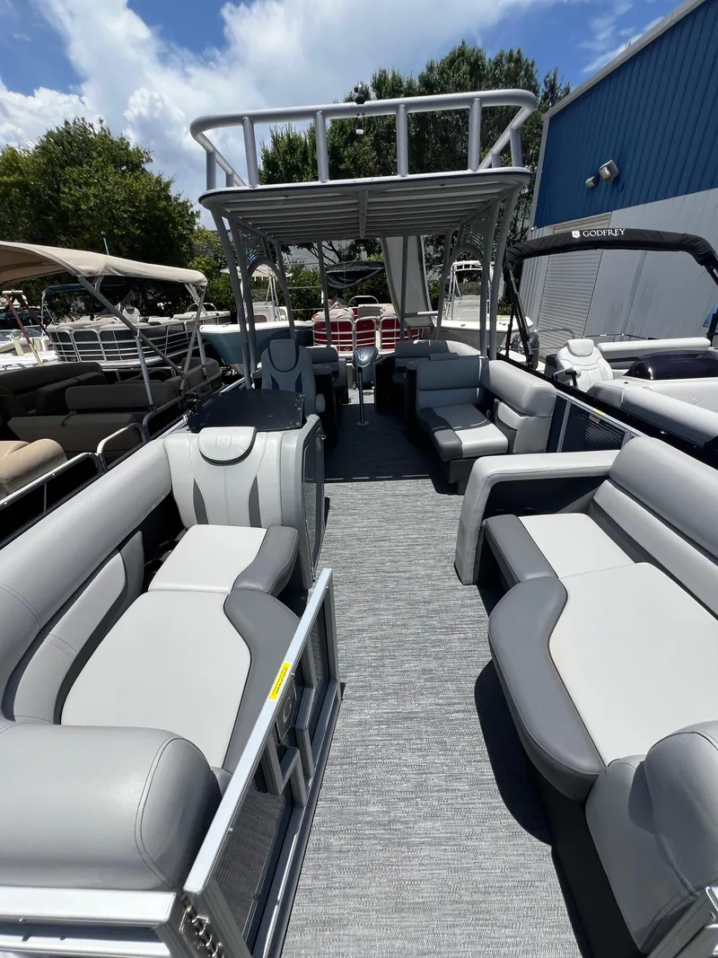 Slide: The Image of 2022 Godfrey Monaco 235 SDB pontoon boat with spacious seating and upper deck under sunny sky. - 11