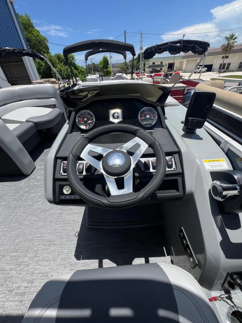 Slide: The Image of 2022 Godfrey Monaco 235 SDB boat dashboard with steering wheel and controls. - 2