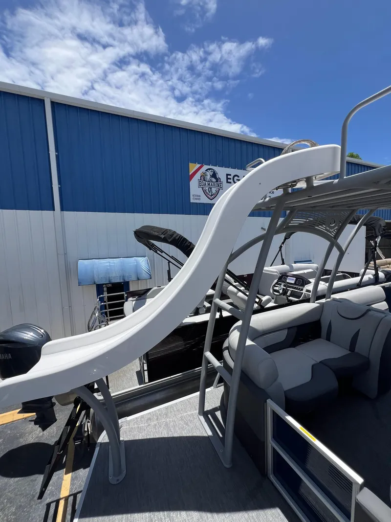 Slide: The Image of 2022 Godfrey Monaco 235 SDB pontoon boat with slide, docked near a blue building. - 29