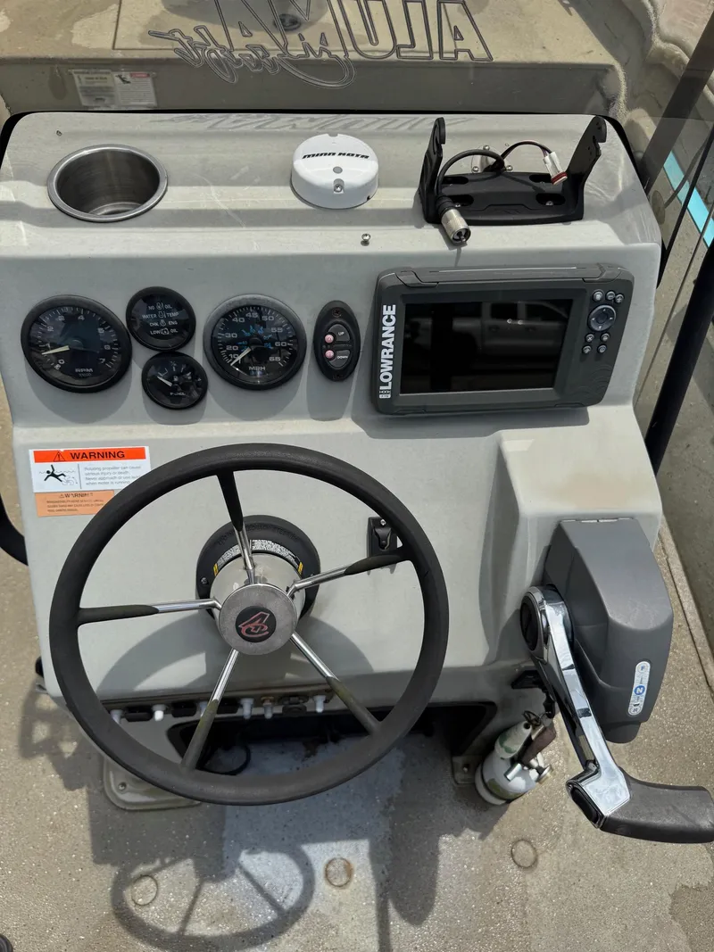 Slide: The Image of 2018 Alumacraft 1860 Bay boat dashboard with steering wheel, gauges, and Lowrance display. - 10
