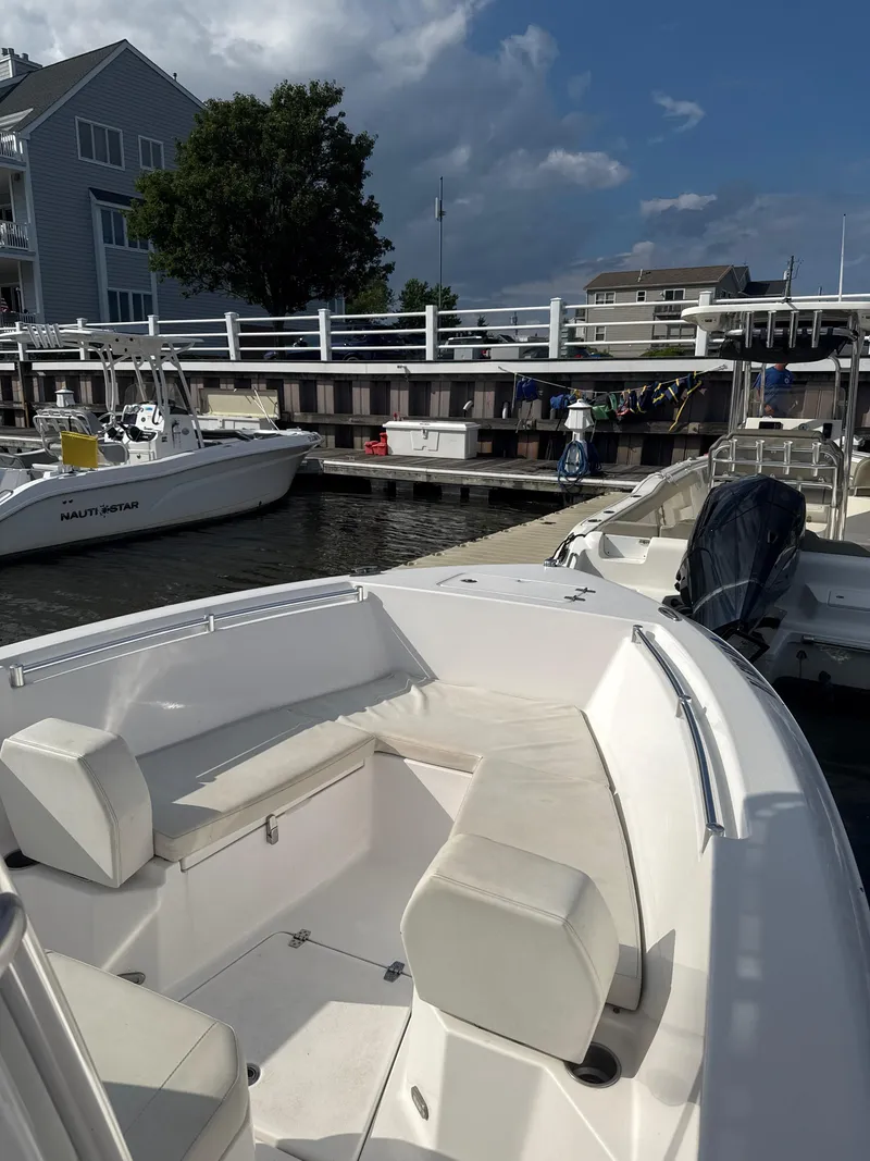 Slide: The Image of 2024 Aquasport 2200 Center Console boat docked at marina under cloudy sky. - 1