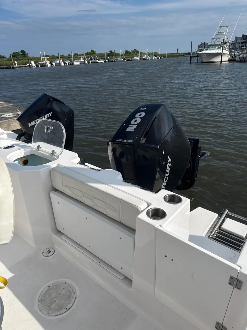Slide: The Image of 2024 Aquasport 2200 Center Console boat with dual Mercury engines docked by the water. - 4