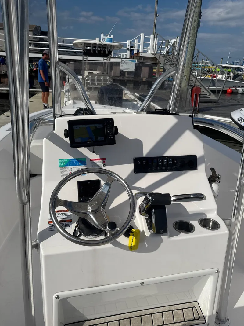 Slide: The Image of 2024 Aquasport 2200 Center Console boat dashboard with steering wheel and navigation equipment. - 5